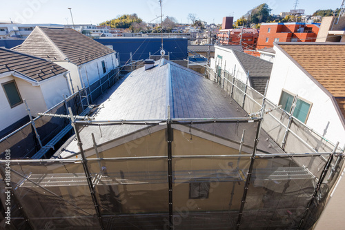 足場と養生シートに囲まれた住宅のリフォーム工事現場、日本の住宅街の俯瞰