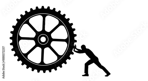 A man pushing a large gear wheel in an industrial setting with effort and strength.