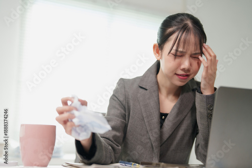 Obraz na plátně Young Asian businesswoman feeling stressed and overwhelmed, holding crumpled pap