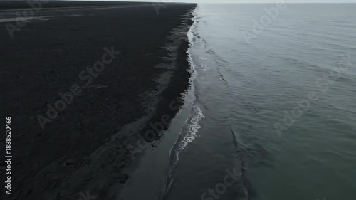 Wallpaper Mural Dramatic contrast between black volcanic sand shoreline and calm ocean waves under an overcast sky Torontodigital.ca