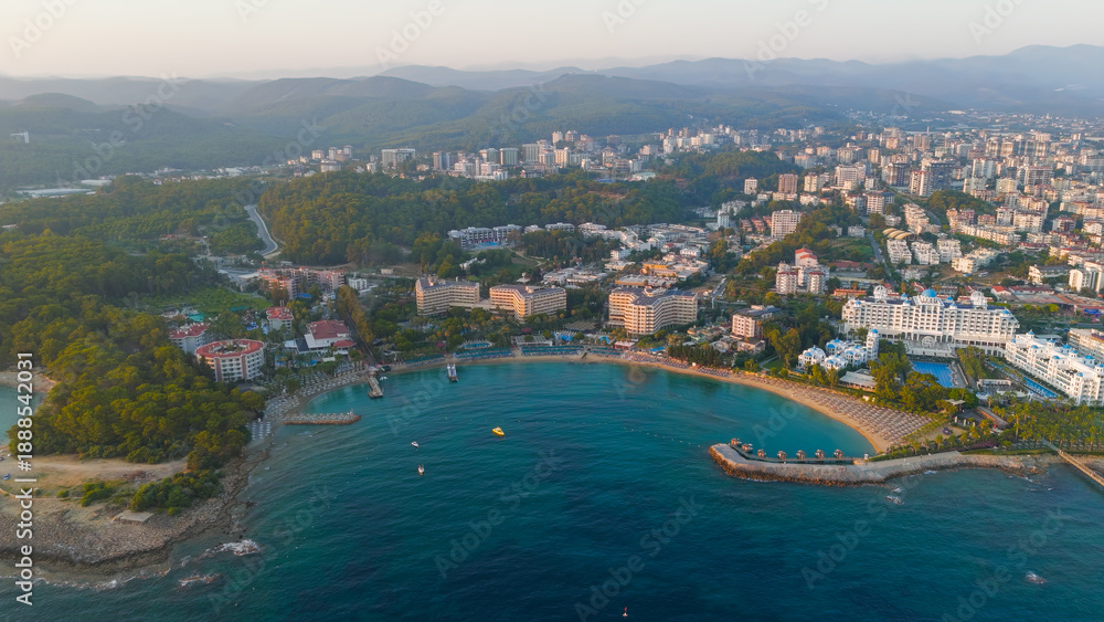Fototapeta premium Avsallar, Alanya, Turkey. Evening panorama of a resort-lined bay with private beaches, city and mountain views.. Aerial View