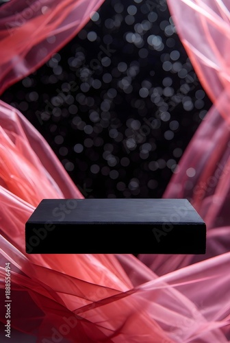An elegant black podium is displayed with flowing red fabric and a bokeh background, creating a luxurious and sophisticated presentation setting