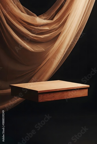 A minimalist, elegant wooden podium floats suspended beneath a flowing, sheer fabric against a dark background, evoking a sense of sophistication and artistry