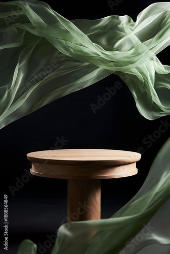Elegant wooden podium featuring gracefully flowing green fabric against a dramatic dark background, creating a minimalist and sophisticated display for concepts or high-end products