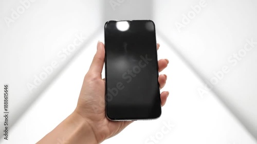 Hand holding a modern smartphone with a blank black screen against a white background