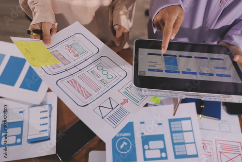 Close up ux developer and ui designer brainstorming about mobile app interface wireframe design on table with customer breif and color code at modern office.Creative digital development agency.