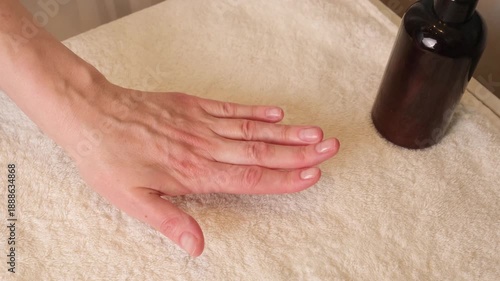 Close up of a woman resting her hand on a towel and examining natural nails, calm home scene focused on manicure care, nail health, skin condition, and routine hand maintenance.