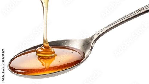 Golden honey pouring into silver spoon