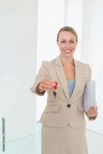 Offering keys on red fob, holding folder, 30s woman beige suit light-blue blouse at home