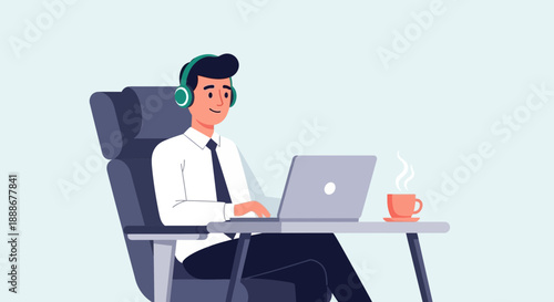 Young man with headphones works on a laptop at his desk with a coffee cup nearby