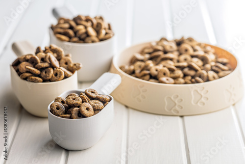 Dry kibble pet food. Dog or cat food in scoop on white table. © Jiri Hera