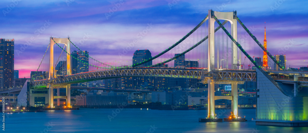 Naklejka premium Tokyo Rainbow Bridge Illuminated at Night with City Skyline and Bay Reflections Panorama