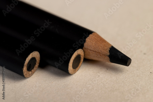 a row of black wooden pencils folded on cheap loose paper, wooden pencils with lead for drawing or other work
