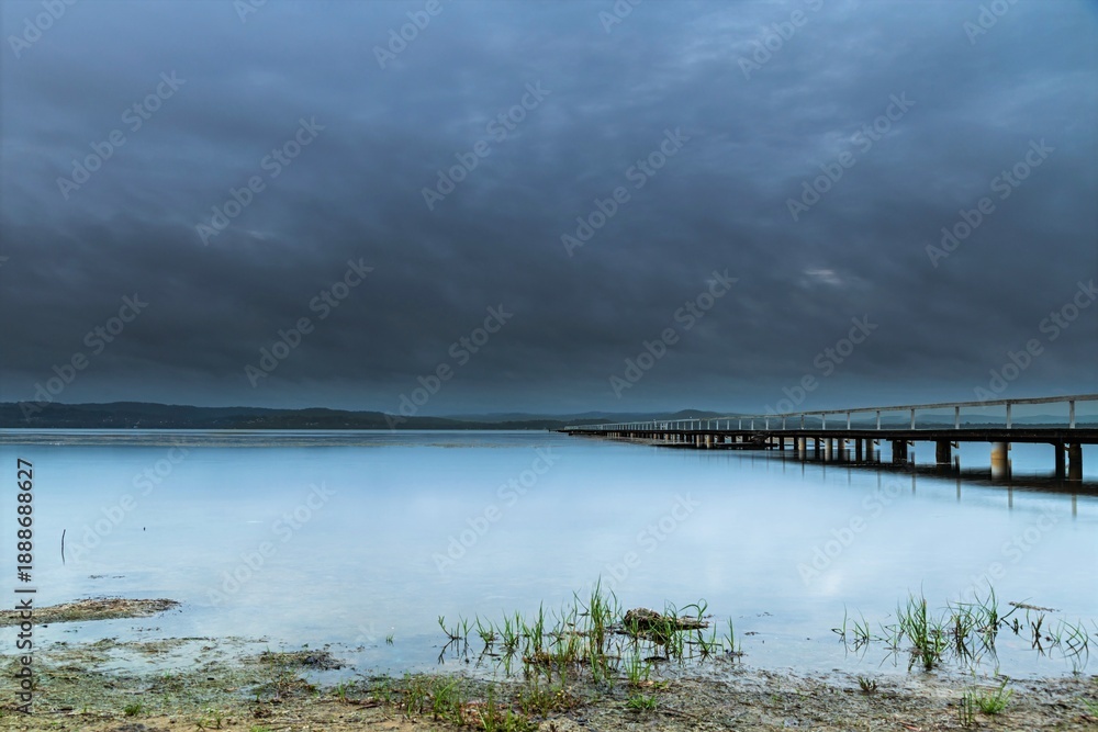 Obraz premium Rainy day sunrise waterscape with wharf