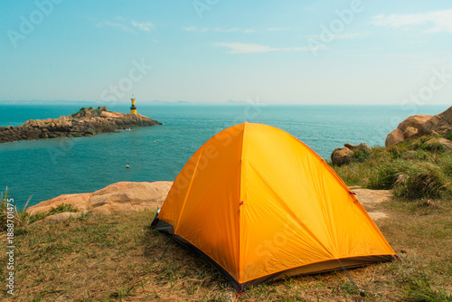 Rocky coastal landscape at Pungdo Island, South Korea, featuring turquoise sea, rugged cliffs, and a small backpacking campsite surrounded by forested