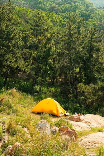 Rocky coastal landscape at Pungdo Island, South Korea, featuring turquoise sea, rugged cliffs, and a small backpacking campsite surrounded by forested