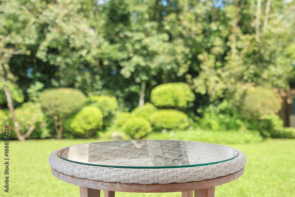 Obraz premium Empty round glass table top with abstract blur green park garden background