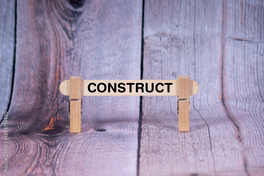 Fototapeta premium Construct symbol. Single Wooden stick supported by Clothespins, beautiful Light Orange tone highlight Wooden Texture Background. Business and Construct concept with copy space