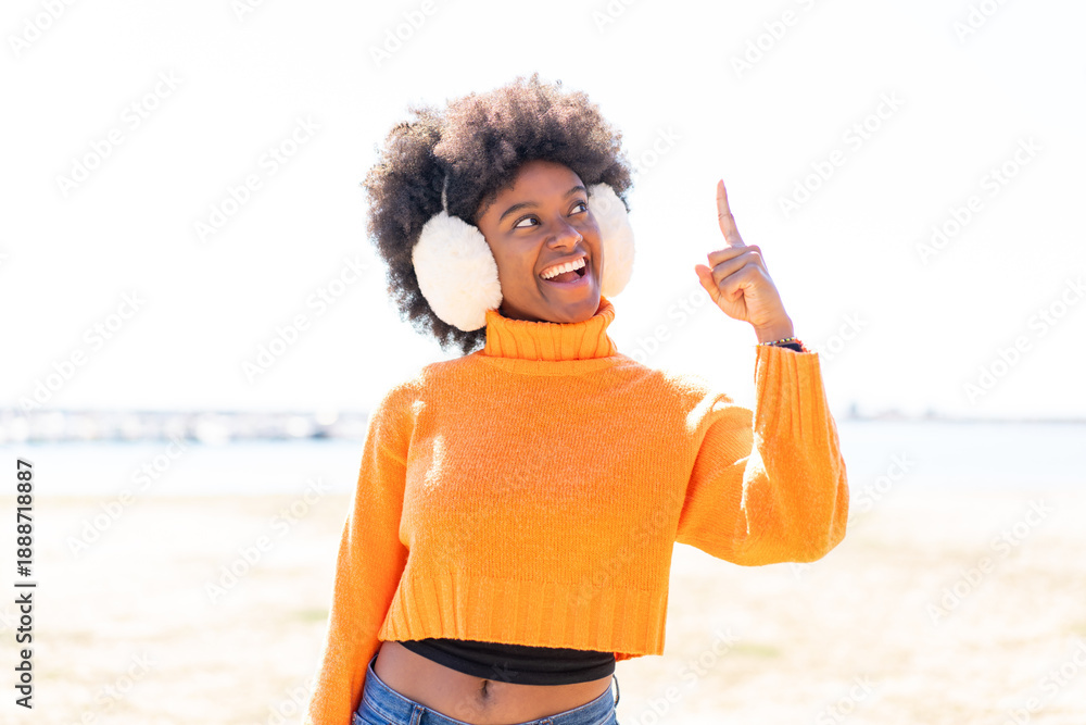 Φωτογραφία African American girl wearing winter muffs at outdoors intending to realizes the