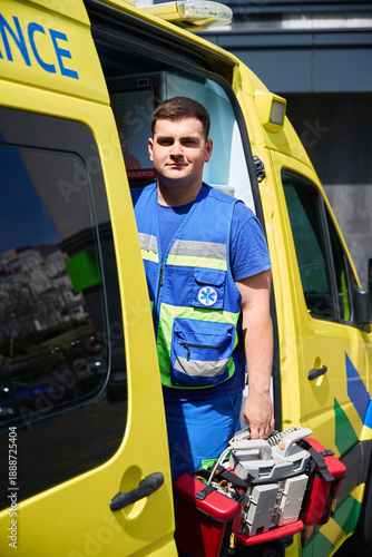 Male paramedic holding defibrillator near ambulance