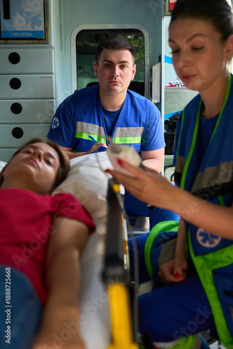 Billede på lærred Medical team responding to female patient emergency in ambulance