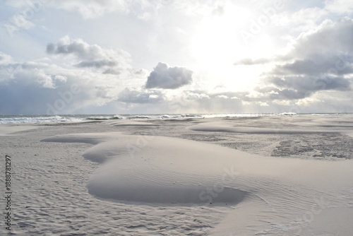 Dramatic stormy sky over an empty sandy beach with waves and dark clouds. Moody seascape landscape with strong wind, cold atmosphere and vast open space. Minimalist coastal scenery, solitude and natur