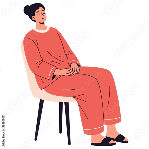 A woman wearing coral pajamas and black slippers sits on a modern chair with her eyes closed and hands clasped in her lap sitting resting calm relaxed