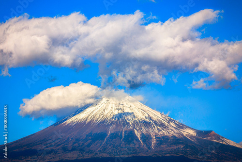 Obraz na plátne Snow‑covered Mount Fuji with white clouds drifting across a blue sky in Fuji, Sh