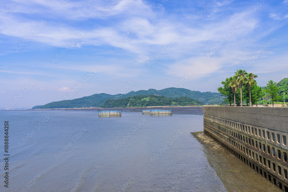 Obraz premium 青空を背景に 「潮風が運ぶ、防波堤から見える海と遊歩道」 宇土市観光スポット(宇土マリーナおこしき館) With a blue sky as a backdrop 