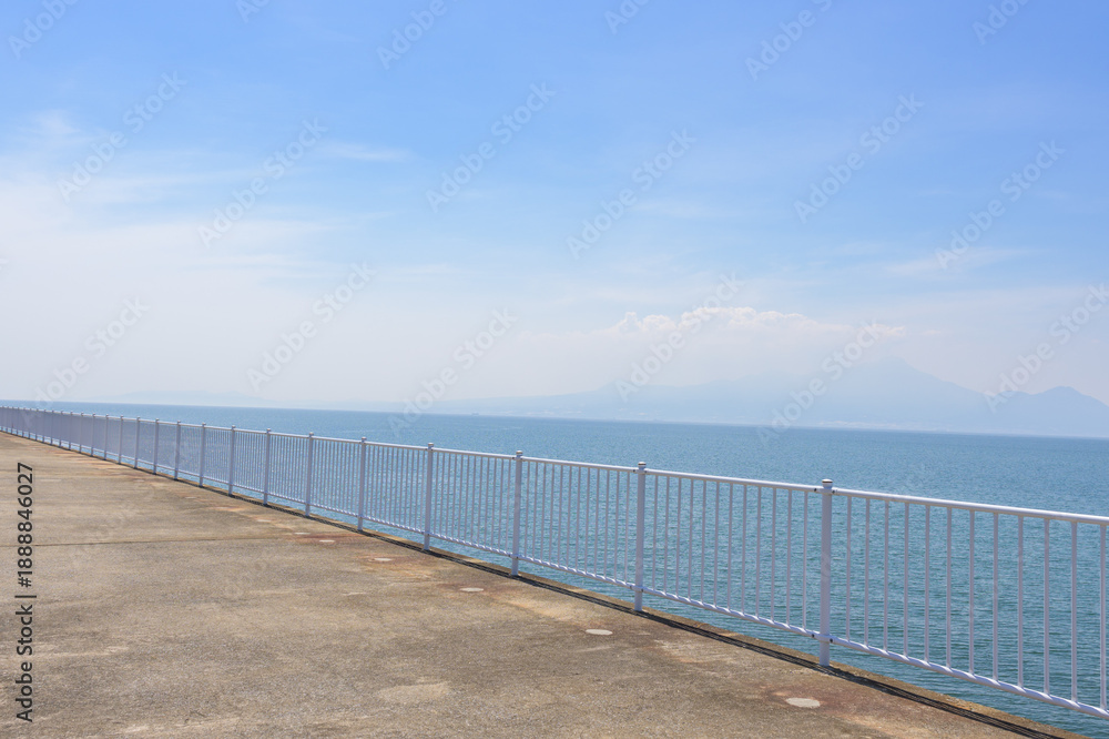 Obraz premium 青空を背景に 「潮風が運ぶ、防波堤から見える海と遊歩道」 宇土市観光スポット(宇土マリーナおこしき館) With a blue sky as a backdrop 