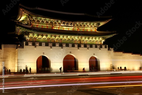 Night view of illuminated Gwanghwamun Gate with traffic light trails in Seoul.