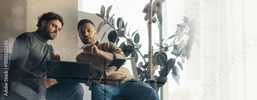 Cuadro en lienzo Two men are seated in a bright room, engaged in a work discussion