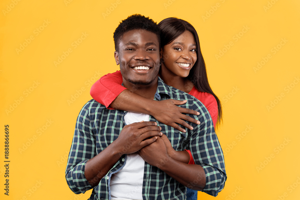 Naklejka premium A man and woman stand close together, smiling widely. The man has short hair and wears a checkered shirt, while the woman has long hair and wears a red top. They both appear happy.