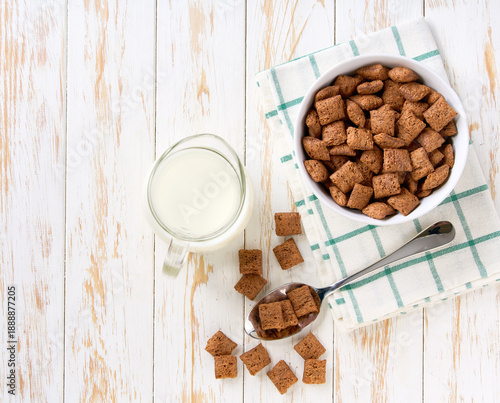 Making a healthy breakfast cereal using crispy chocolate pillows and milk. Top view.