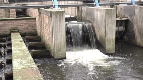 Water flows through a water treatment facility in an urban area near a river during the afternoon