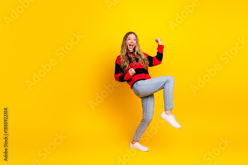 Joyful young woman in casual knitwear, cheerfully expressing herself against a vibrant yellow background showing style and fun