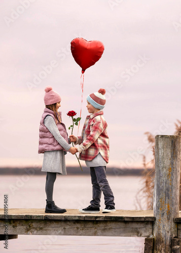 lovely boy gives a red rose and red heart balloon to his girlfriend