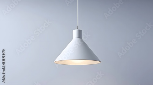 A clean minimalist white pendant lamp with a conical shade is suspended from the ceiling emitting a soft warm glow perfect for modern home decor and interior design