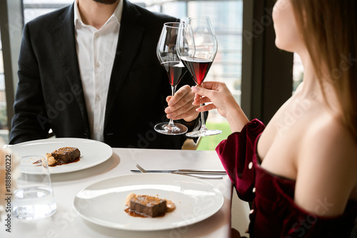 Young couple celebrating while toasting wineglasses in a luxury restaurant, cropped
