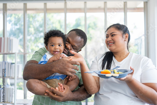 Happy family bonding while feeding their baby in a bright home setting. Promotes healthy parenting, emotional connection, and modern lifestyle through nurturing care and joyful interaction
