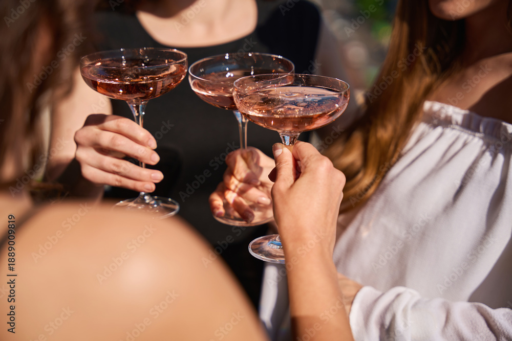 Fototapeta premium Close up of women holding cocktails toasting outdoors