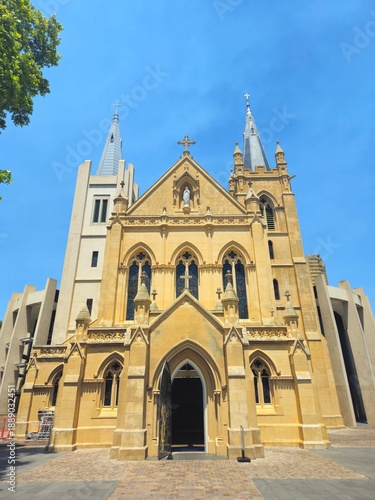 The soaring St Mary’s Cathedral in Perth interior featuring limestone arches, ornate ceiling, colorful stained glass, and a central altar. Wooden pews line the nave while banners hang beside columns