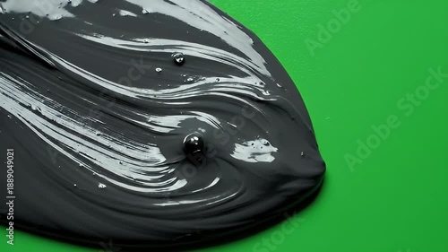 Black Paint Swirl on Green Background in Artistic Visual Exploration