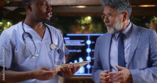 Doctor presenting medical project to senior business executive during professional meeting, followed by handshake symbolizing healthcare partnership, investment agreement, or strategic collaboration.