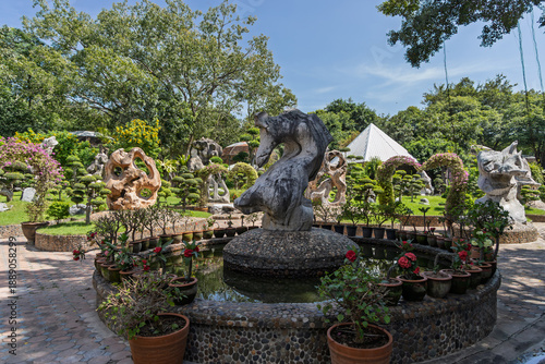 ornamental fountain with stone sculptures surrounded by potted plants at the million years stone park pattaya thailand