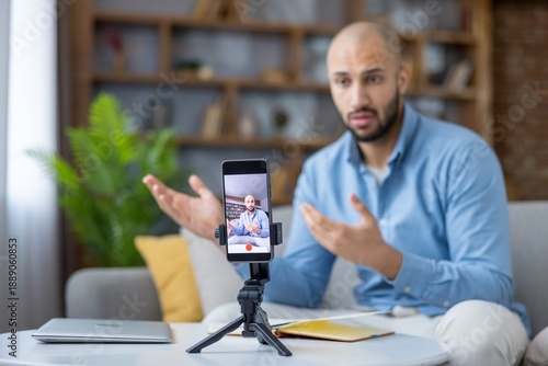 Canvas-taulu Young man creating online content at home, filming himself with a smartphone on