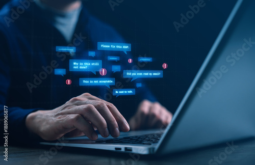 Hands typing on a laptop as hostile digital messages appear, representing workplace cyberbullying and toxic remote work, highlighting stress, conflict, and mental health issues in online offices.