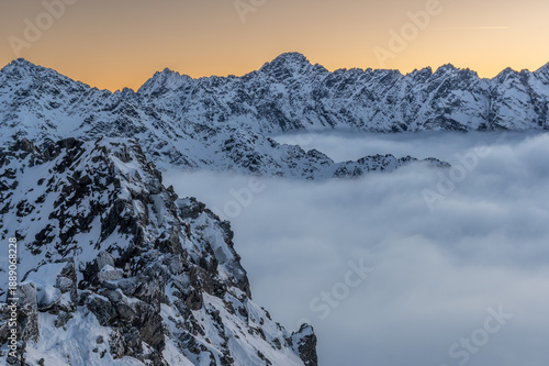 Winter sunset view of High Tatra mountains, with valleys filled by clouds, seen from Szpiglasowy Wierch to the Hruby Peak, Poland, Slovakia