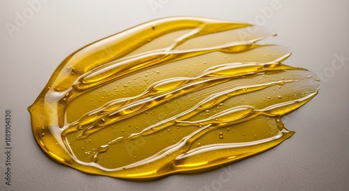 Thick golden liquid oil or honey swatch with visible bubbles and streaks, macro detail on dark surface