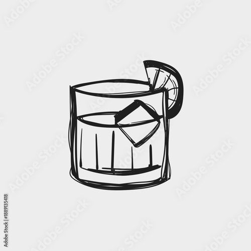 Cocktail with ice and lemon slice sits on a flat surface in a simple setting during the evening time